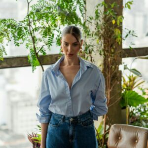 Fashionable woman in a light-filled urban indoor garden with city views.