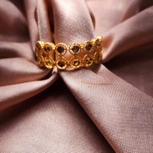 Close-up of a gold ring placed on luxurious pink fabric, highlighting texture and elegance.