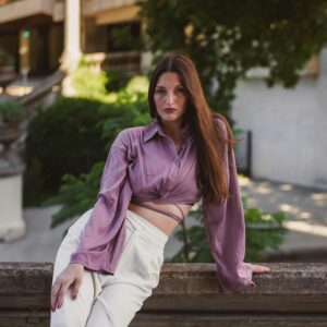 Stylish woman in elegant outfit posing in an outdoor setting, exuding confidence.