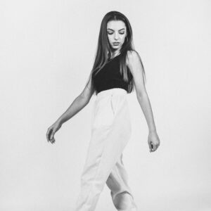 Black and white full body of young female in casual clothes standing in studio and looking down